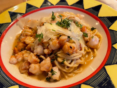 Makaron spaghetti z krewetkami, natką i płatkami parmezanu na talerzu