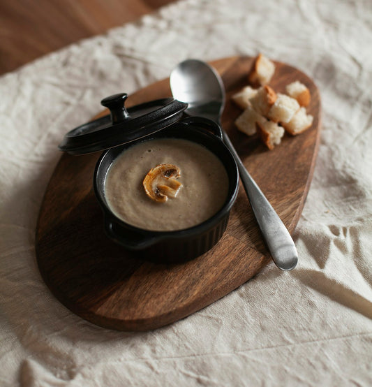 Kremowa zupa pieczarkowa w ceramicznej miseczce z grzankami i plasterkiem pieczarki