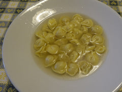 Tortellini in brodo w klarownym bulionie na białym głębokim talerzu