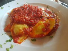 Ravioli z ricottą w sosie pomidorowym na białym talerzu