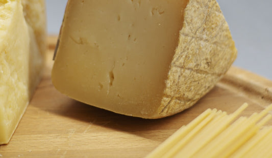Klin dojrzewającego sera parmezan Parmigiano Reggiano z makaronem spaghetti