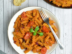 Makaron fusilli z tuńczykiem w sosie pomidorowym na białym talerzu