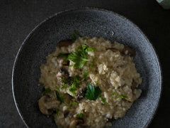 Risotto z grzybami posypane natką pietruszki w ciemnej misce