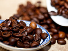 Palone ziarna kawy na porcelanowym spodku - arabica i robusta różnią się kształtem i smakiem