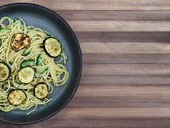 Spaghetti z cukinią posypane parmezanem i pieprzem na talerzu