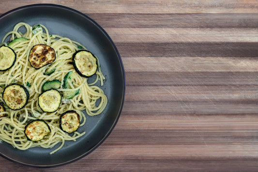 Spaghetti z cukinią posypane parmezanem i pieprzem na talerzu