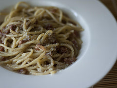 Pasta alla gricia z guanciale, pecorino i czarnym pieprzem na białym talerzu