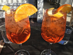 Aperitivo po włosku - dwa kieliszki Aperol Spritz z pomarańczą na słońcu