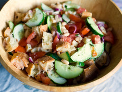 Panzanella w drewnianej misce: kawałki chleba, pomidory, ogórek i czerwona cebula